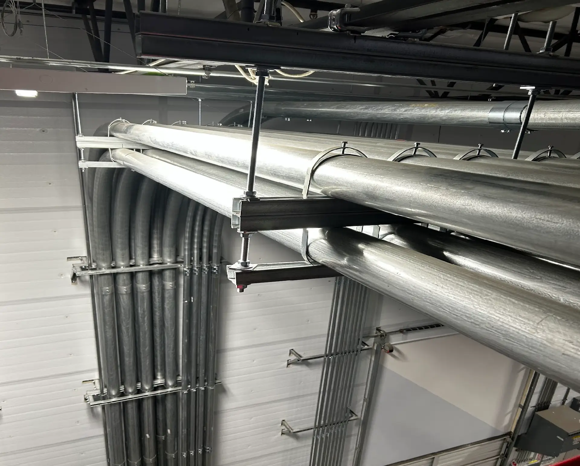 Insulated metal pipes and conduits overhead in an industrial ceiling.