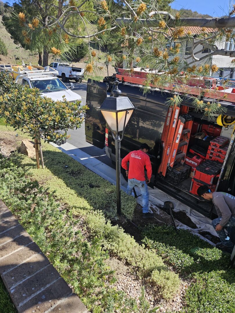 Workers operating a crane to place large rocks in a garden area.